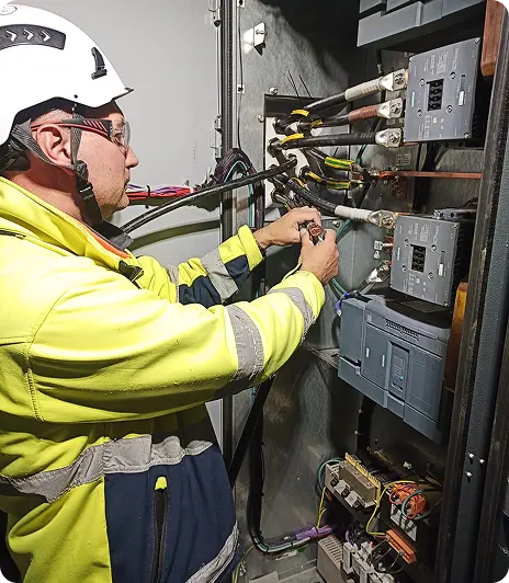 Elektryk wykonujący prace przy rozdzielnicy przemysłowej